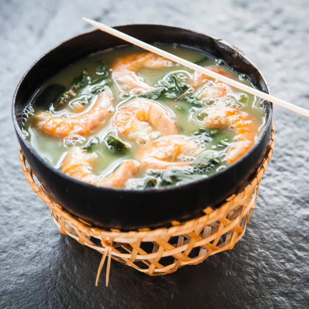 Cuias de tacacá com caldo amarelo, goma de tapioca, camarão e folhas de jambu