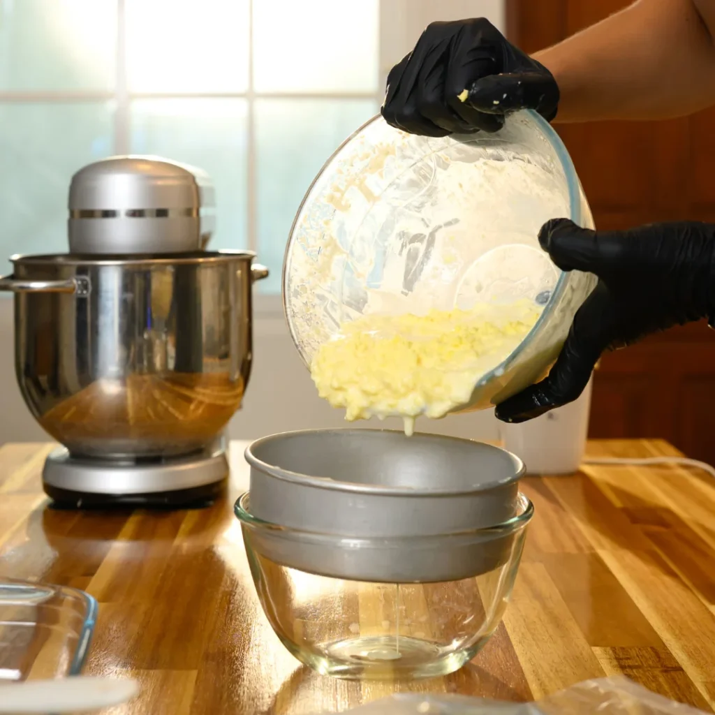 Manteiga sólida e líquido amarelado (buttermilk) em tigela durante batimento