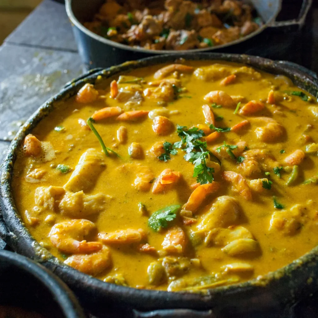 Moqueca com peixe e camarão servida em panela de barro, com pimentão, coentro e leite de coco