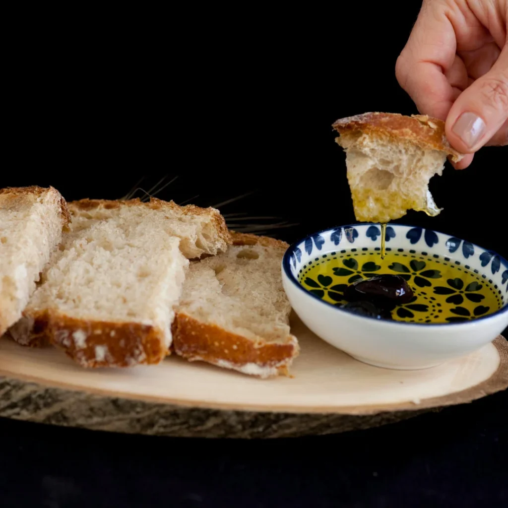 Tigela com azeite e ervas ao lado de fatias de pão italiano